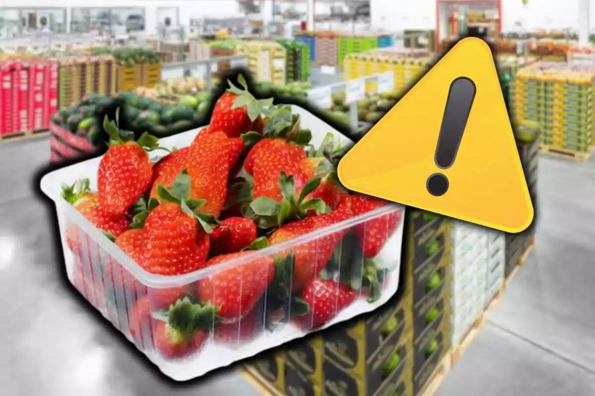 Montaje con triangulo de alerta en la esquina superior iquierda y una caja de fresas en el centro sobre fondo de almacén de frutas supermercado desenfocado