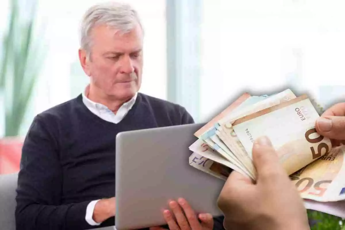 Hombre mayor usando una computadora portátil mientras alguien cuenta billetes de euro.