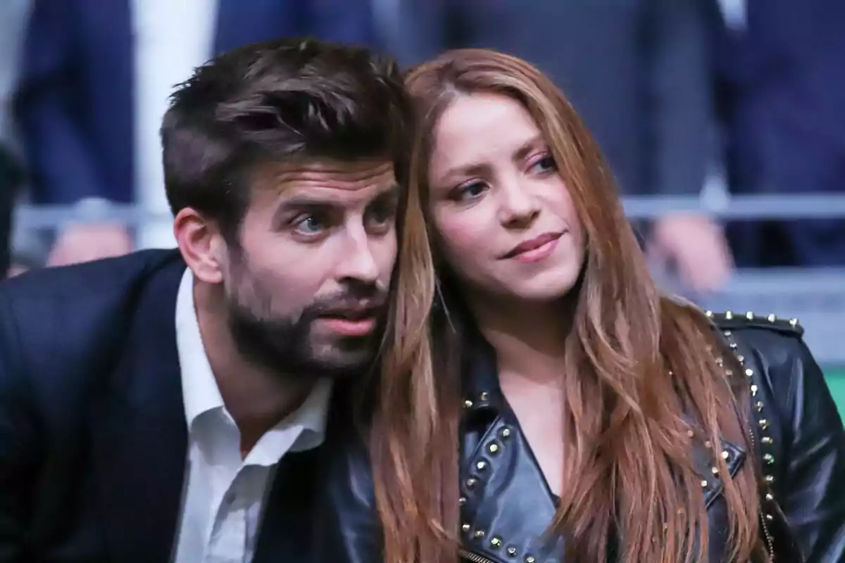 Gerard Piqué and Shakira sitting together, one with a leather jacket and the other with a dark suit, at an event. Gerard Piqué and Shakira sitting together, one with a leather jacket and the other with a dark suit, at an event.