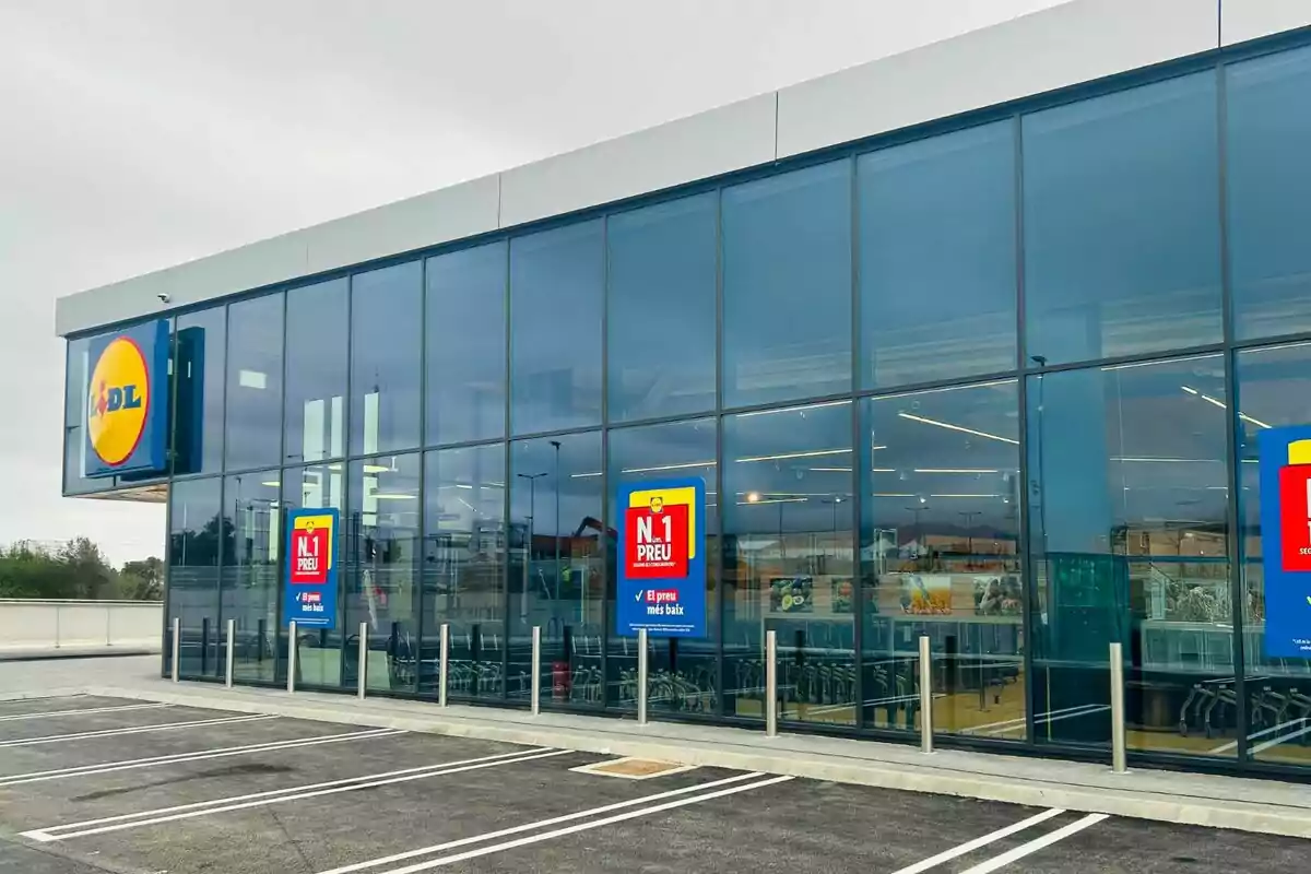 Façana d'un supermercat amb grans finestrals de vidre i un cartell publicitari a l'exterior.