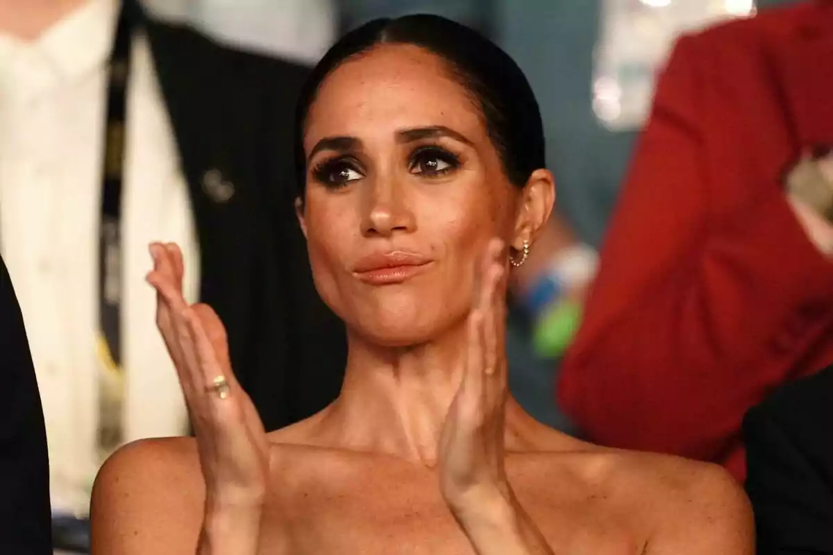 Meghan Markle aplaudiendo con expresión seria en un evento.