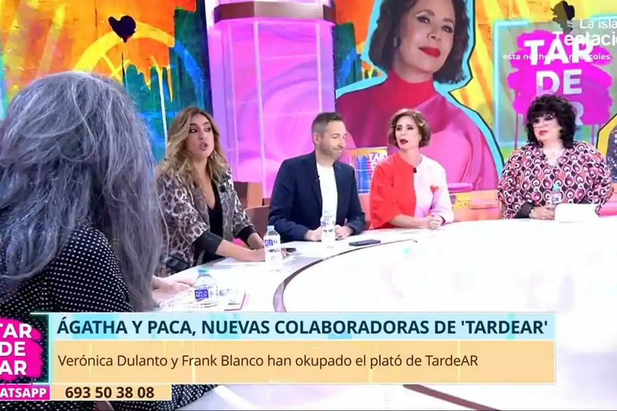 Mario Vaquerizo, Verónica Dulanto, Frank Blanco, Ágatha Ruiz de la Prada y Paca la Piraña está sentado alrededor de una mesa en un set de TardeAR colorido, con un gran retrato de una mujer en el fondo.