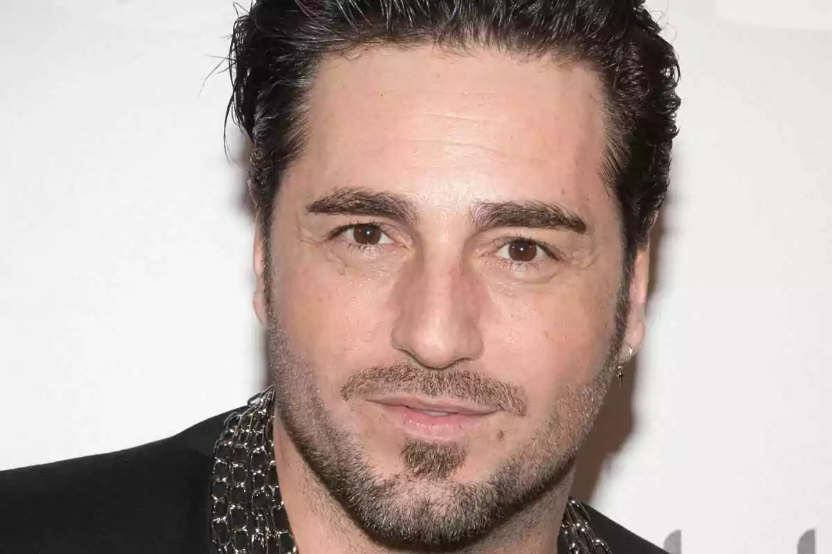 Un hombre con barba y cabello oscuro mira a la cámara con una expresión neutral. Un hombre con barba y cabello oscuro mira a la cámara con una expresión neutral.
