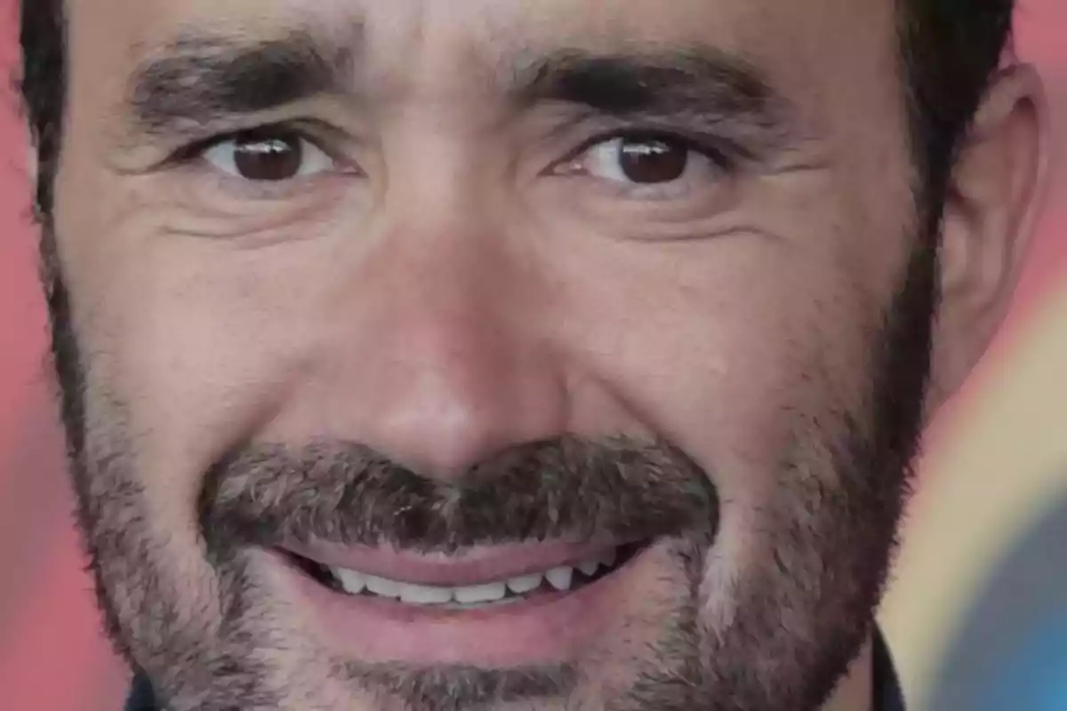Un hombre con barba y expresión facial sonriente.