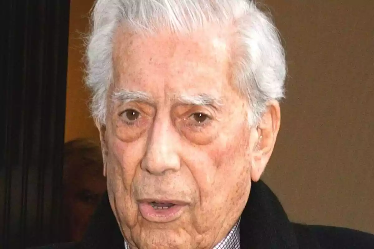 Primer plano de Mario Vargas Llosa con el rostro serio mientras sale a la calle desde un edificio