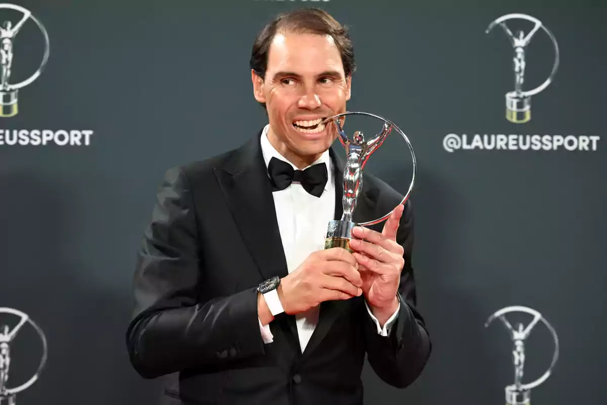 Rafa Nadal in formal attire holding a trophy at a sports award event.